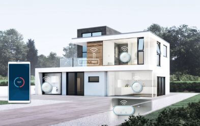 Moderne zweistöckige Villa mit großen Fenstern und weißer Fassade. Das Bild zeigt Symbole von smarten Haushaltsgeräten, die mit dem Haus vernetzt sind. Auf der linken Seite ist ein Smartphone abgebildet, das die Vernetzung mit smarten Geräten darstellt. Im Hintergrund ist ein Garten mit Bäumen zu sehen.